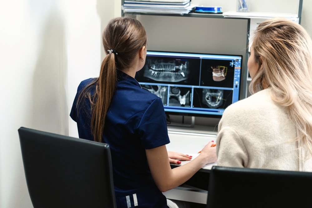 Female,Doctor,Shows,The,Patient,An,X-ray,Image,At,Display.